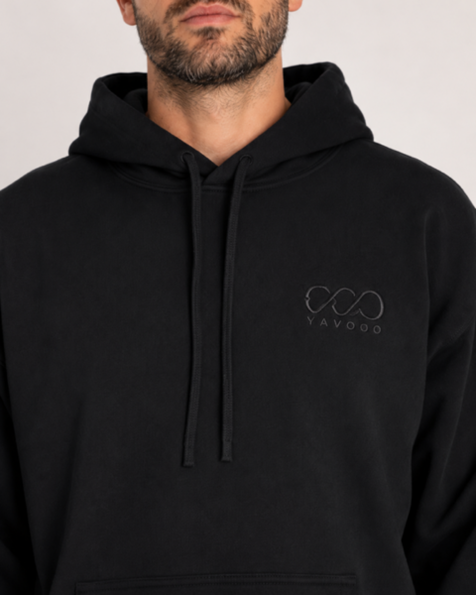 Person wearing a black hoodie with a logo on a light gray background