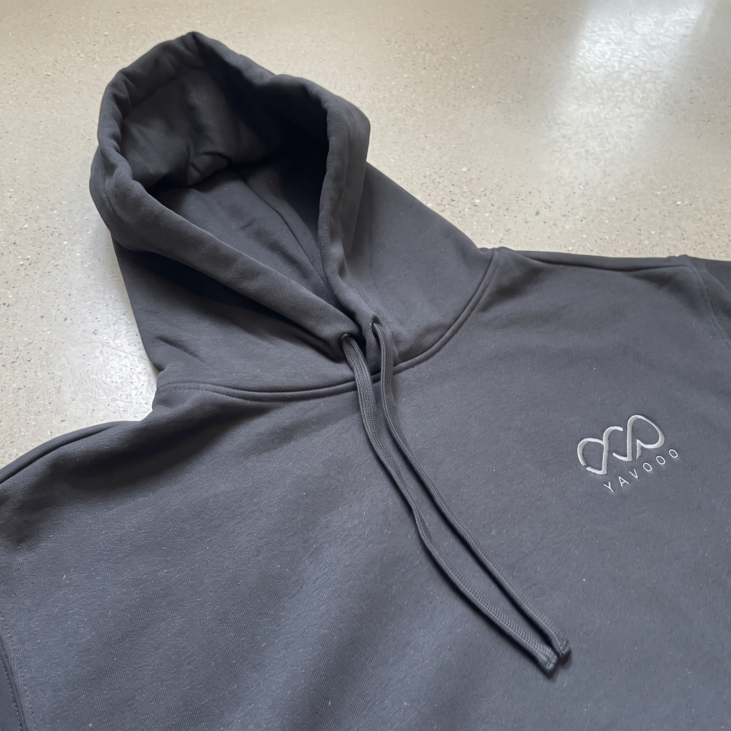 YAVOOO hoodie logo and hood detail, light concrete background